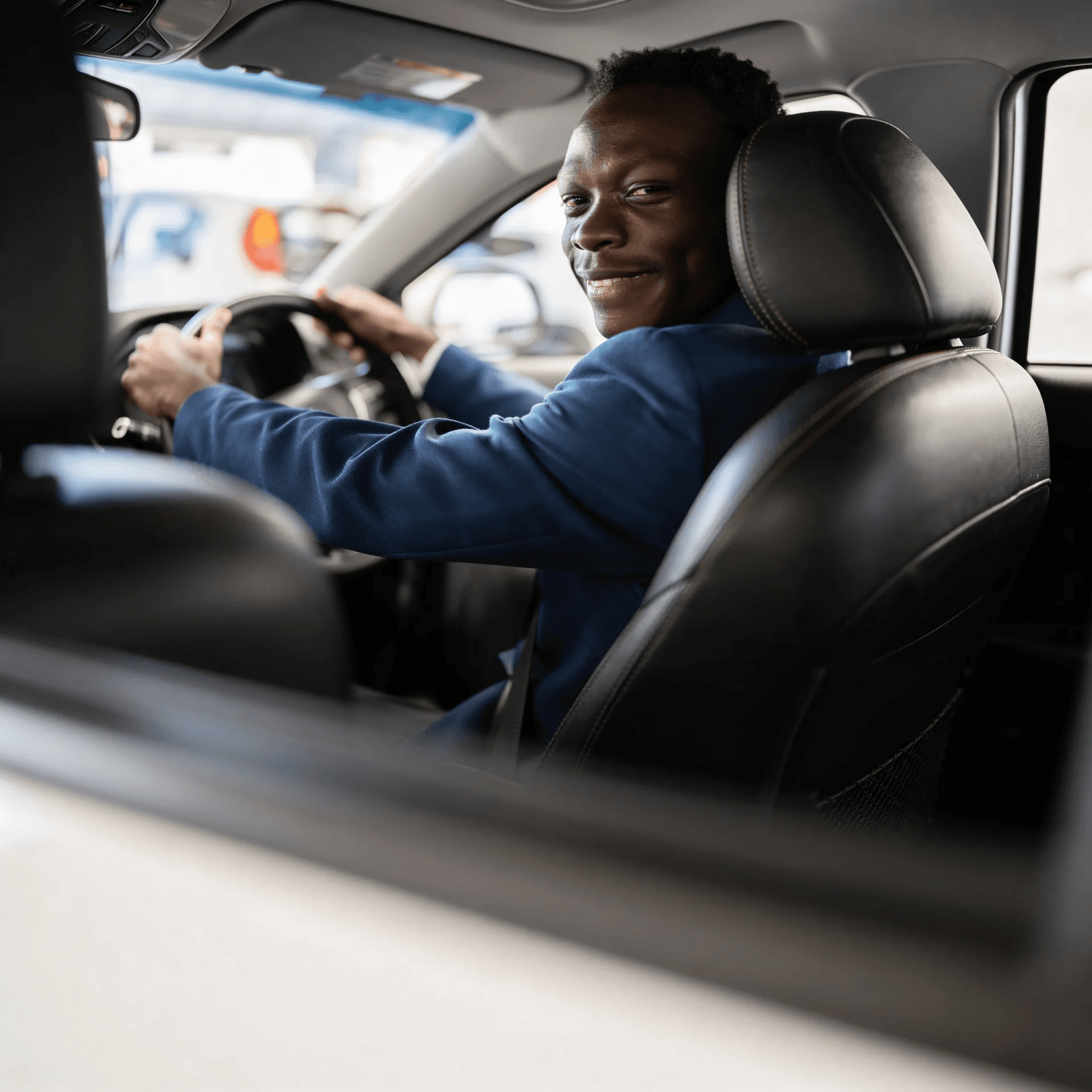 Professional driver smiling back from inside a taxi