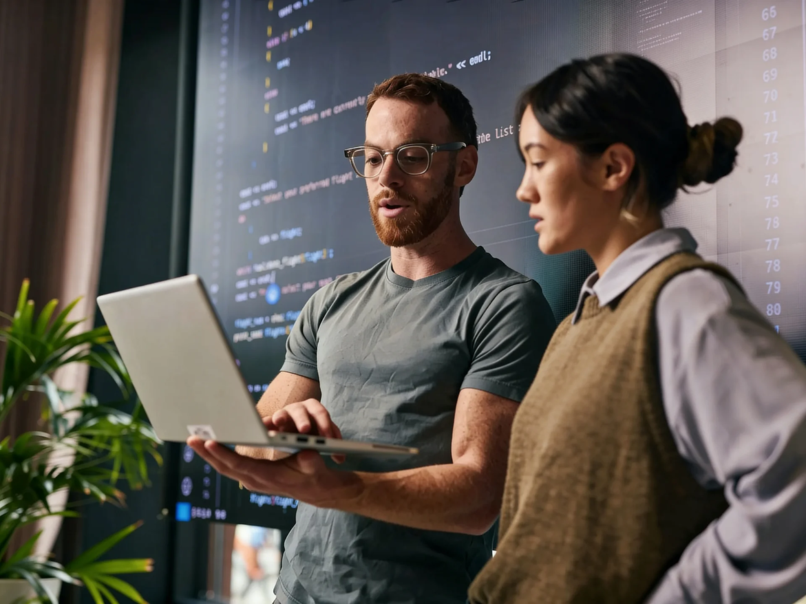 Two product team members reviewing code on a laptop